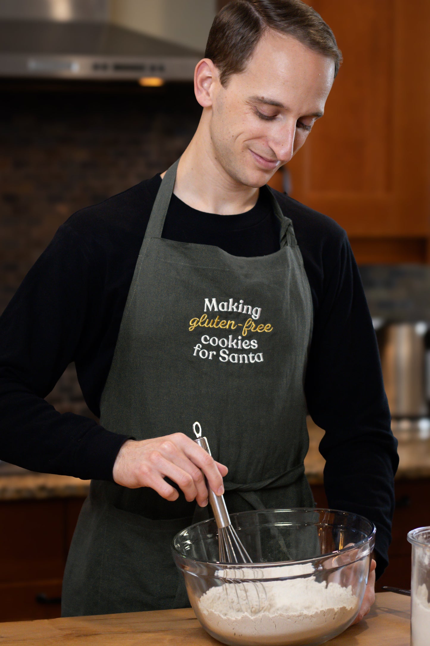 Man wearing green Christmas apron with "Making gluten-free cookies for Santa"